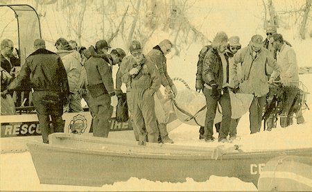 Rescue personnel remove body of victim from icy Convict Lake in the Sierra Nevada, as divers continue to search nearby. Six others died