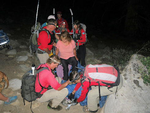 Settling the injured hiker into the wheeled litter Settling the injured hiker into the wheeled litter