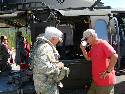 Ops leader and helicopter pilot reviewing plans with victim via cell phone